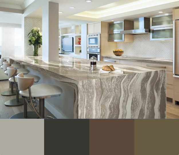 A modern kitchen with a large white quartz countertop island and bar stools. The cabinets are a light gray color with stainless steel handles. The backsplash is a white herringbone tile.