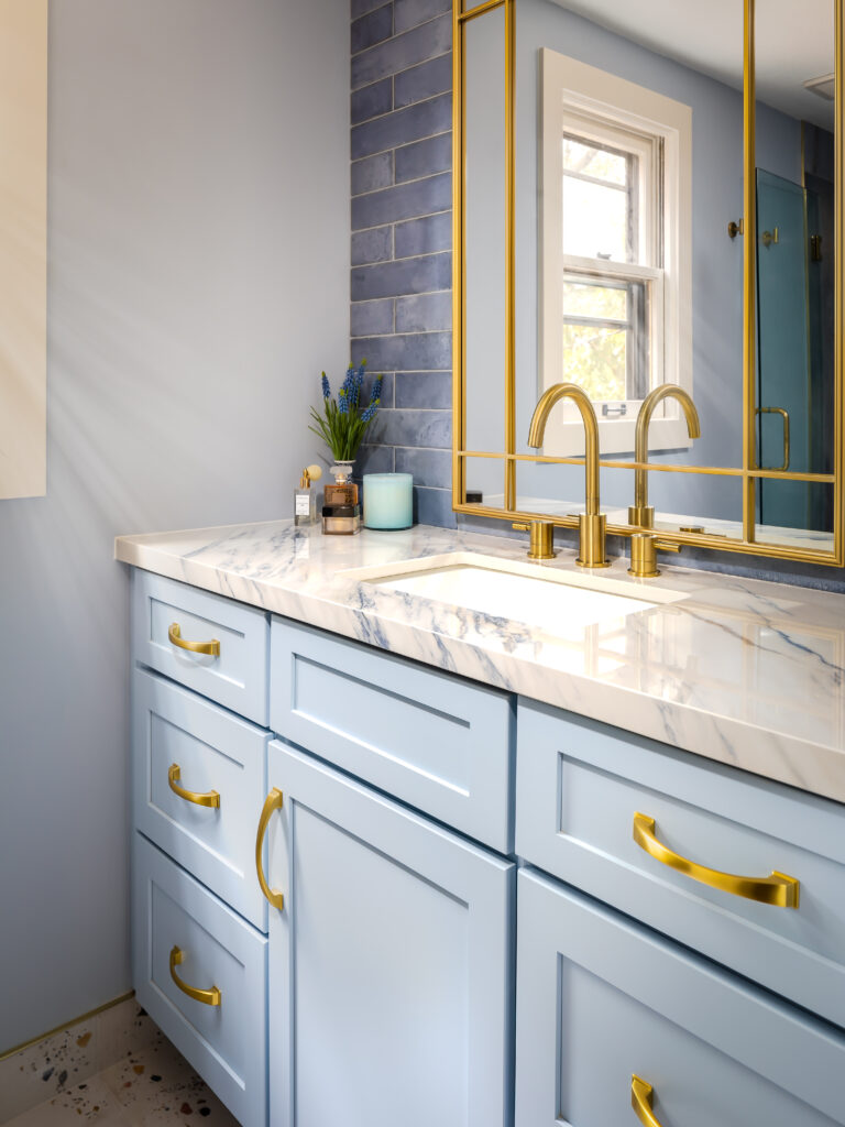 Light blue bathroom vanity with gold hardware.